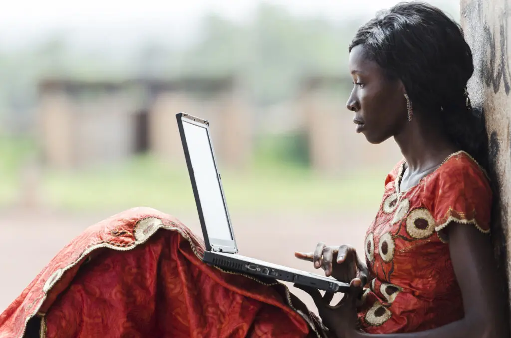Giovane donna africana in abito tradizionale con laptop per TOAfrica