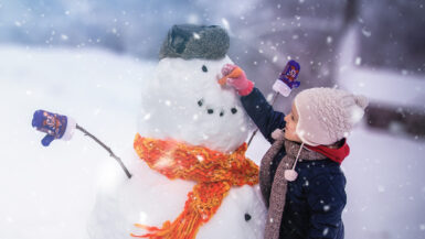 Child sculpts a snowman in a park