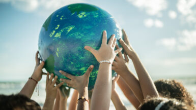 Close-up of children holding a planet at the beach