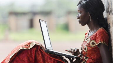 Giovane donna africana in abito tradizionale con laptop per TOAfrica