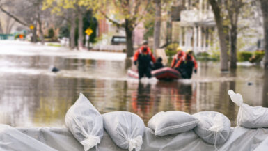 Flood Protection Sandbags with flooded homes in the background (Montage)