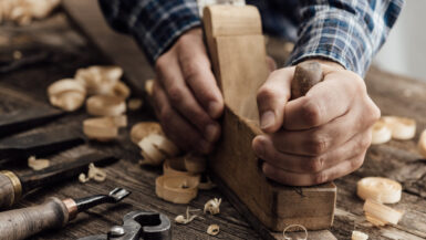 Carpenter working in his workshop, he is smoothing a wooden board using a planer, carpentry, carpentry, woodworking and craftsmanship concept