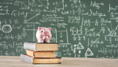 Books with piggy bank in front of green chalk board